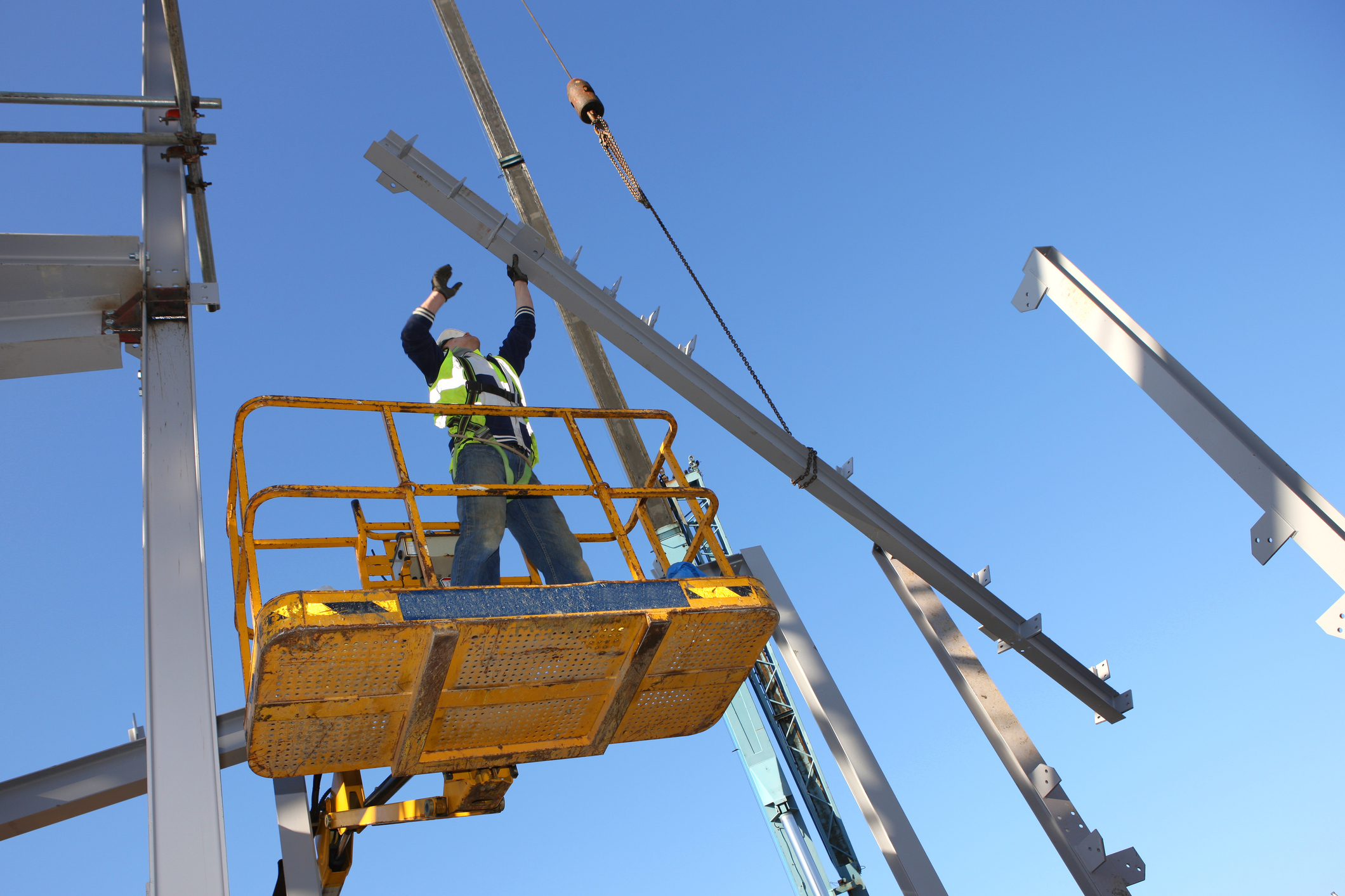 Steel worker on cherry picker. Some motion blur on hands.