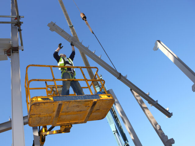 Steel worker on cherry picker. Some motion blur on hands.